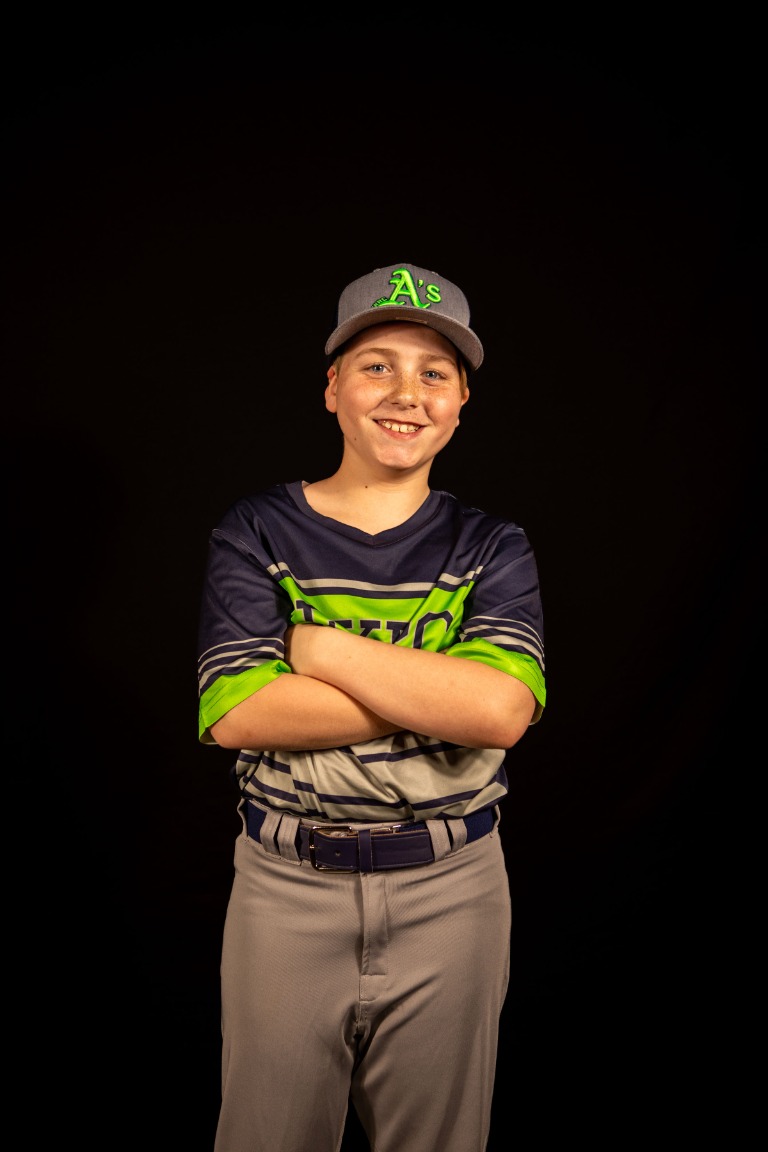 A young baseball player smiling for his portrait