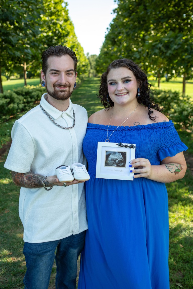 Expecting parents sharing a sunlit moment outdoors