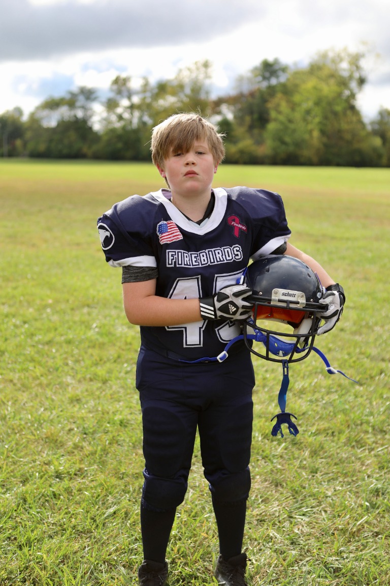A young football player holding his helmet