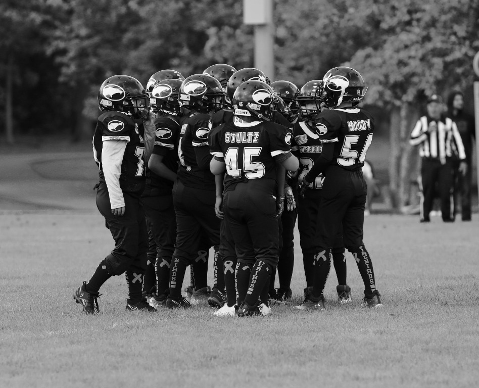 A youth football team gathering for a huddle