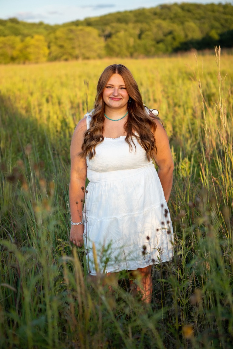 A senior portrait in a white dress in a golden field